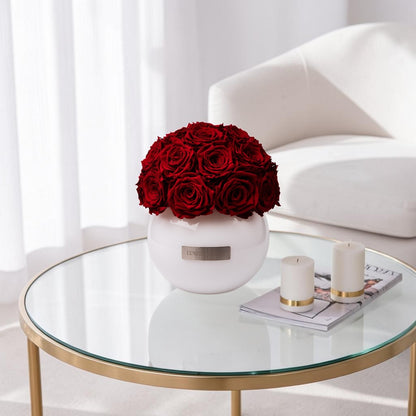 Weisse Glassvase gefüllt mit konservierten Roten Rosen. 